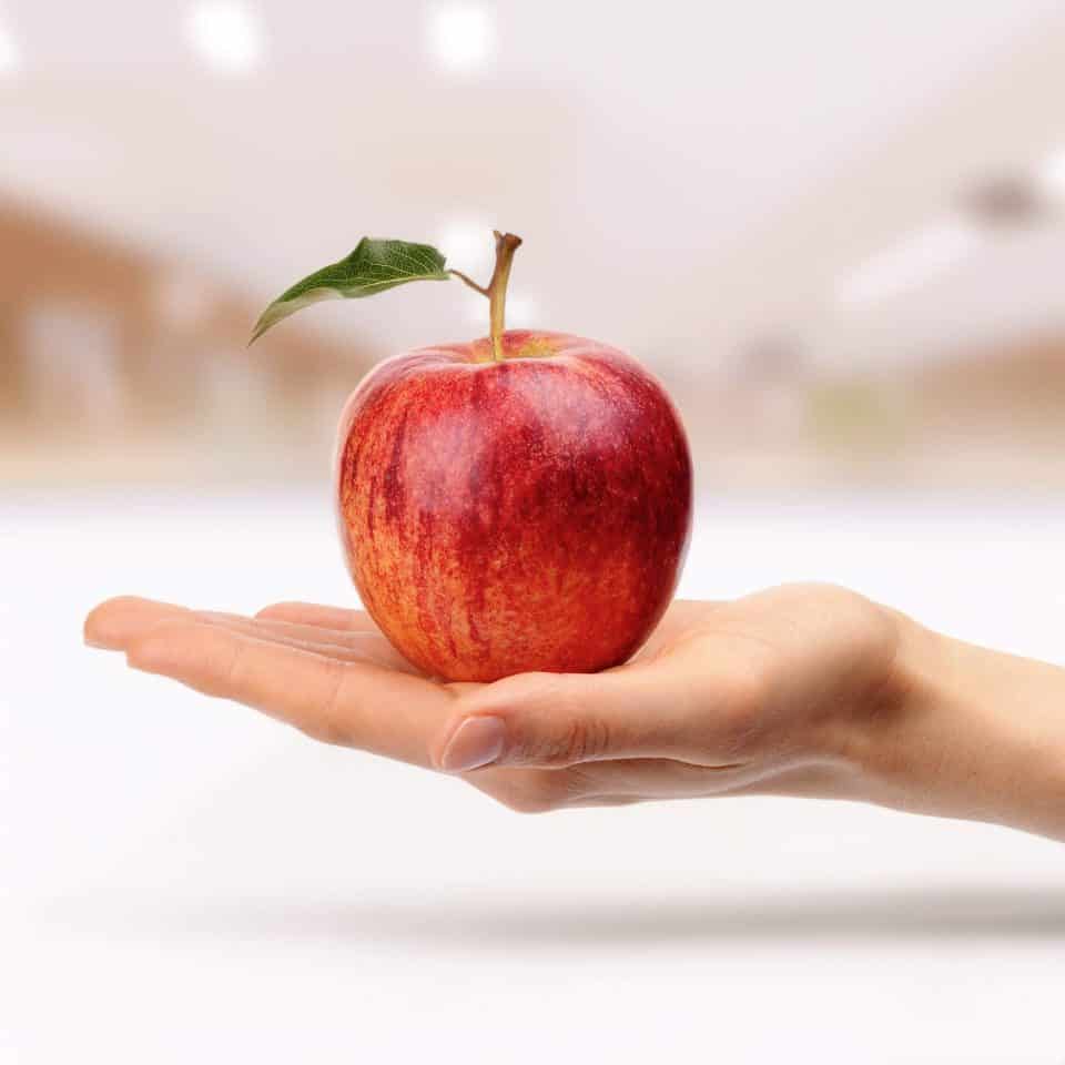 Ein roter Apfel wird in einer Hand gereicht